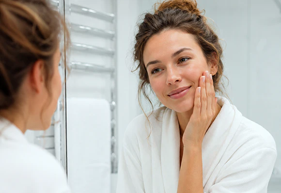 Woman with glowing skin in a mirror